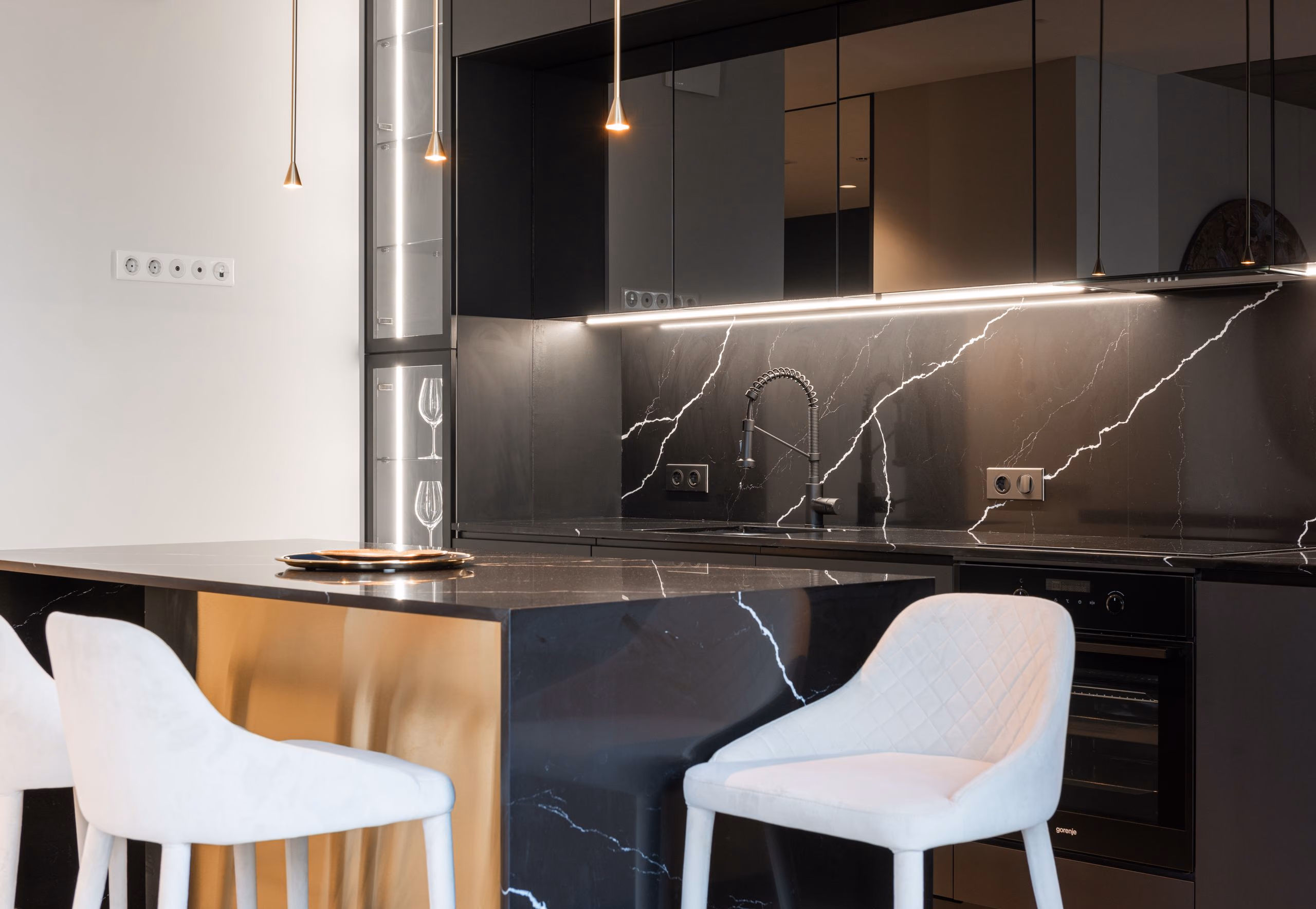 A modern kitchen with a dark marble worktop and brass detailing